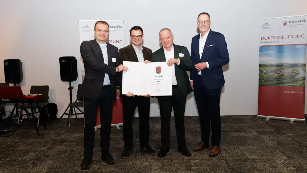 Vier Männer, Volker Probsteder und Marcel Weber vom Bürgerverein Kaan sowie Stadtbürgermeister Gerd Klasen bei der Urkundenüberreichung durch Innenminister Michael Ebling (von links), Michael Ebling, bei einer Urkundenübergabe zur Dorferneuerung Rheinland-Pfalz; zwei halten eine große Urkunde, im Hintergrund stehen Roll-ups